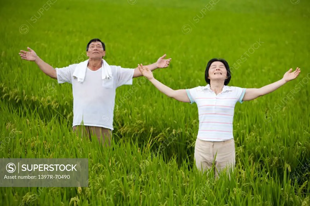 Farmer couple taking deep breath in rice field
