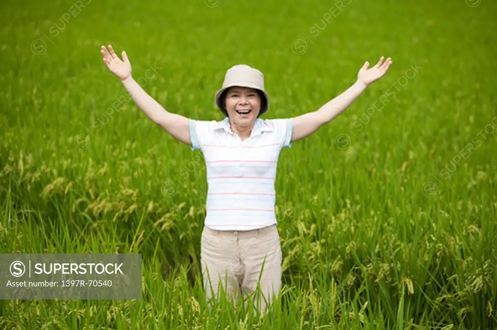 Mature farmer taking deep breath in rice field, smiling