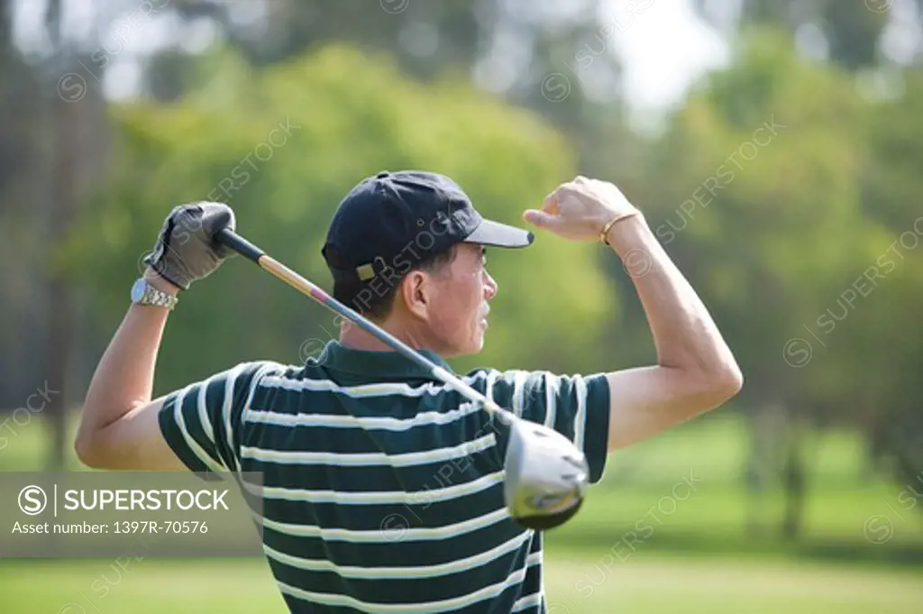Man holding golf swing and looking away