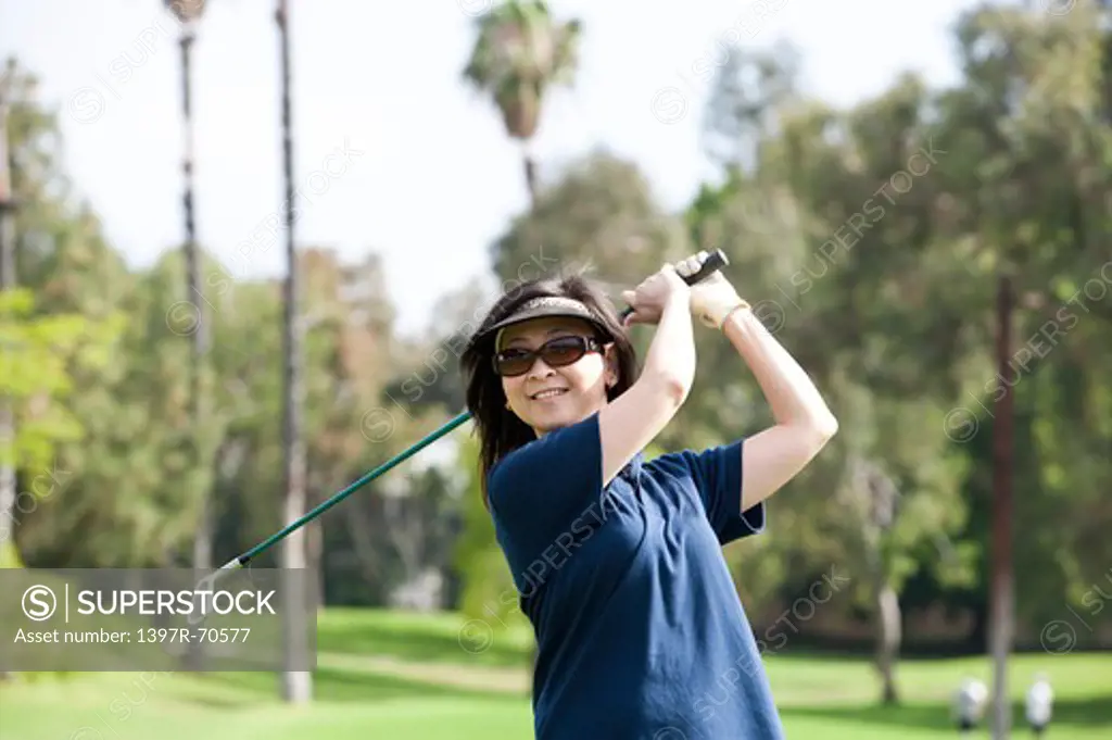 Woman holding golf swing and swinging with smile