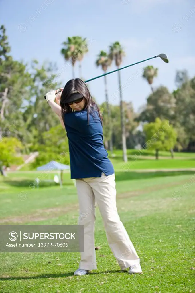 Woman swinging with golf swing and looking down