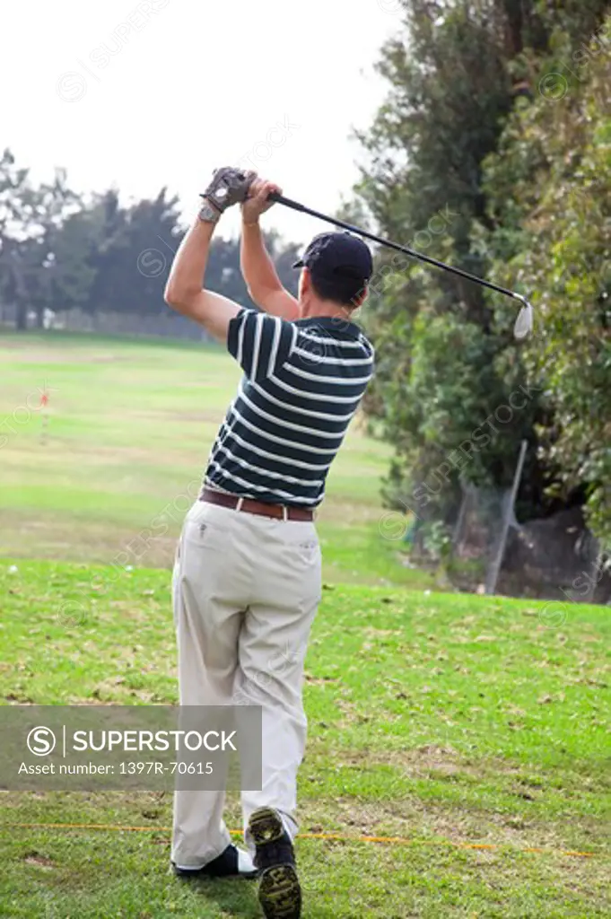 Man standing on the lawn and swinging with golf swing