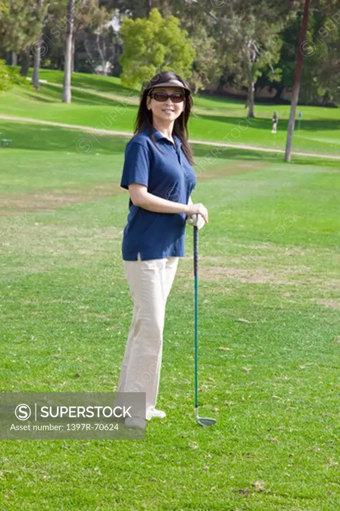 Woman standing on the lawn with golf swing and smiling at the camera