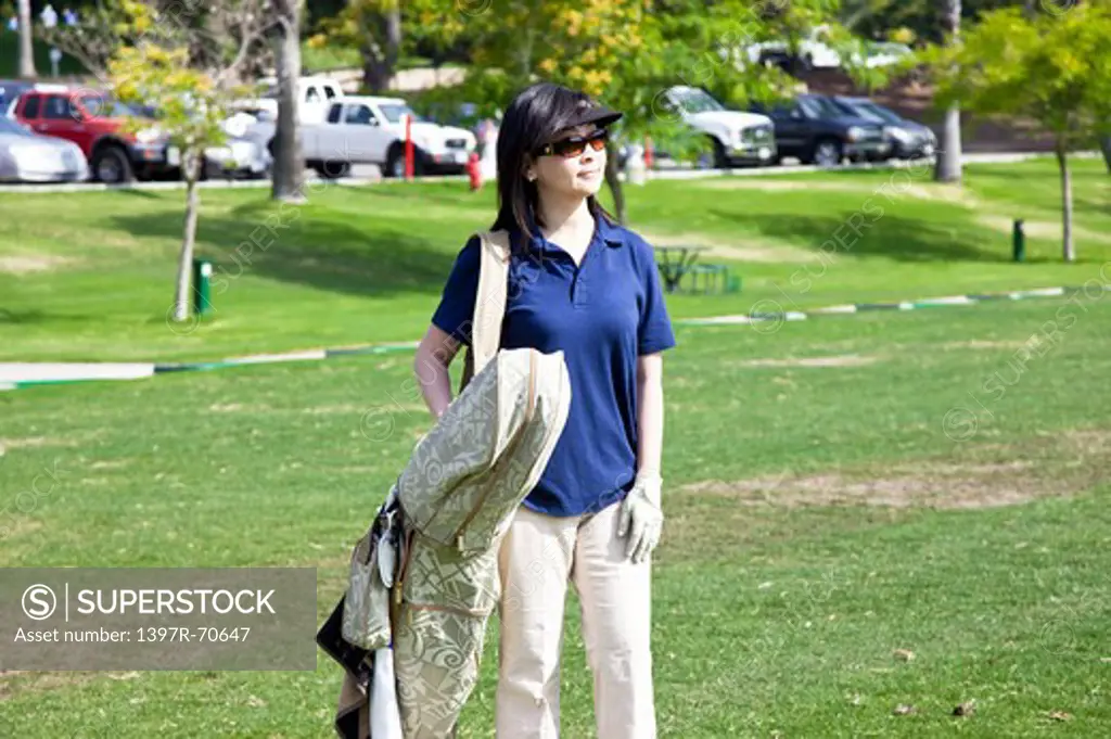 Woman carrying golf bag on the shoulder and looking away