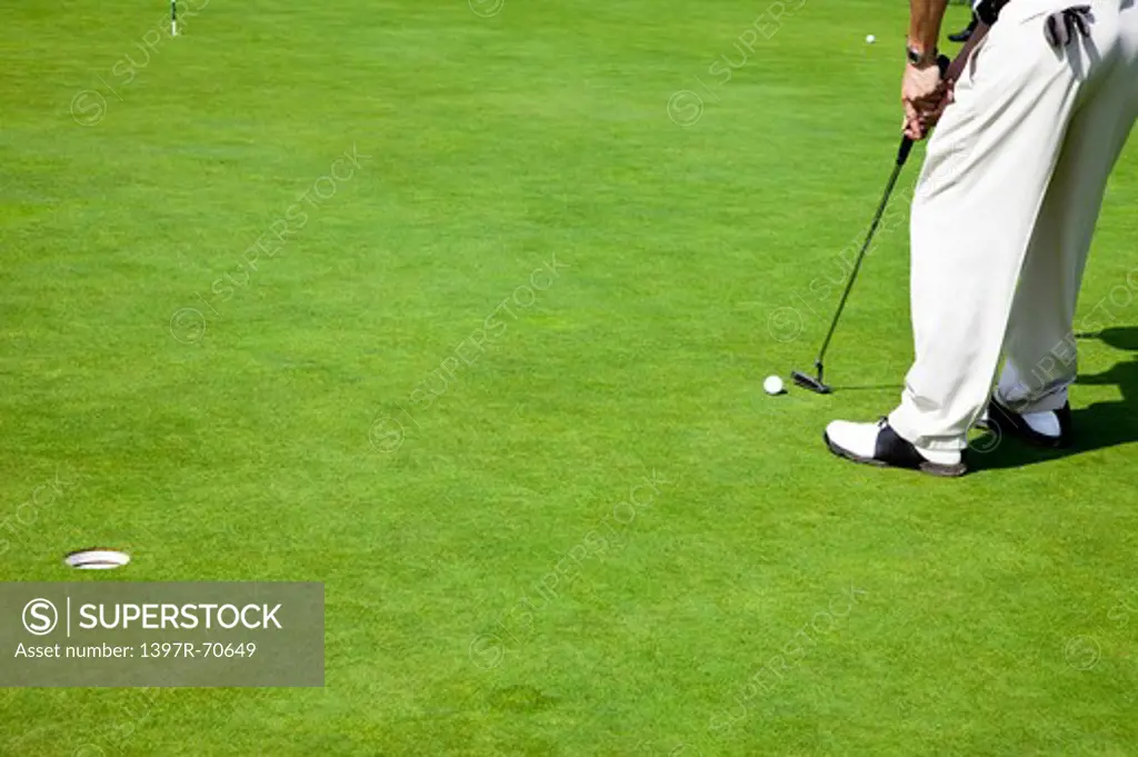 Man holding golf swing and putting golf ball