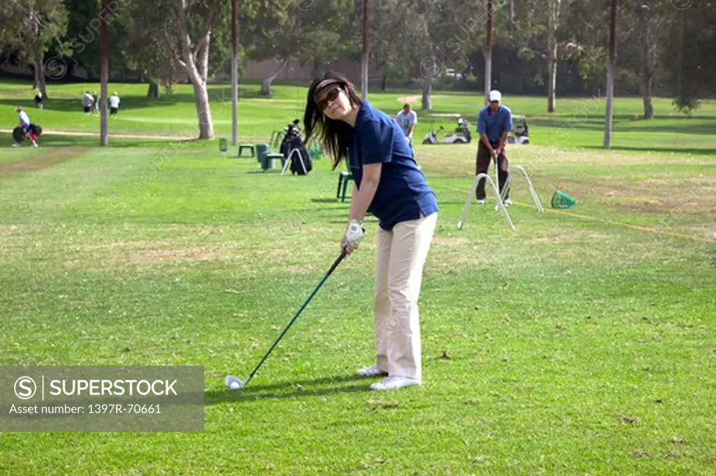 Woman holding golf swing and looking at the camera