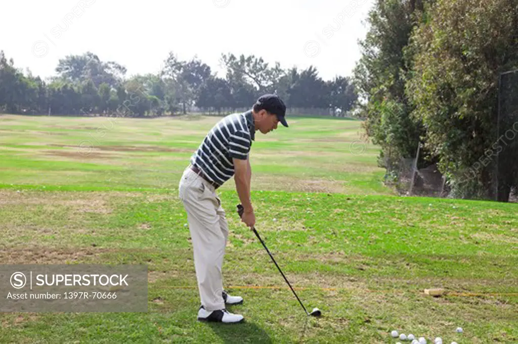 Man standing on the lawn and putting with golf swing