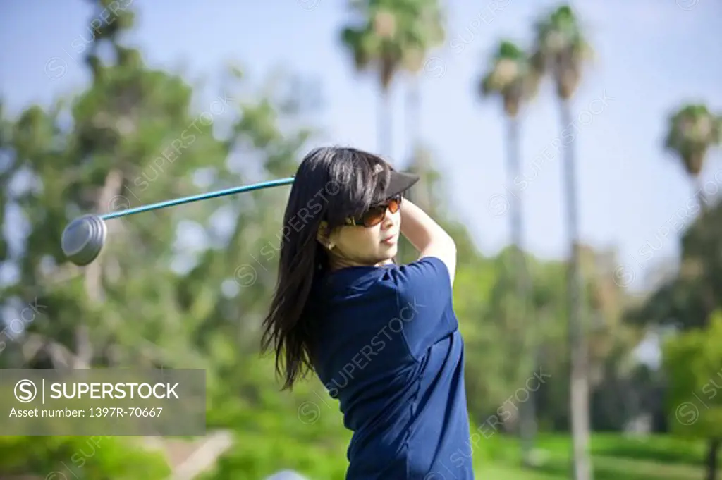 Woman swinging the golf swing and looking away