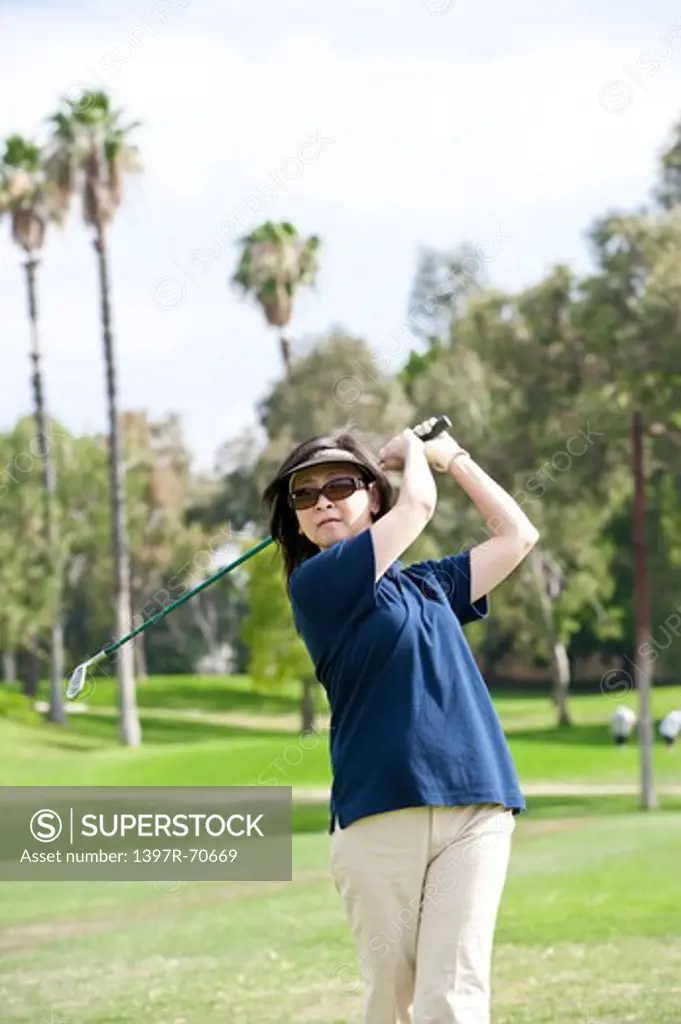 Woman swinging with golf swing and looking away