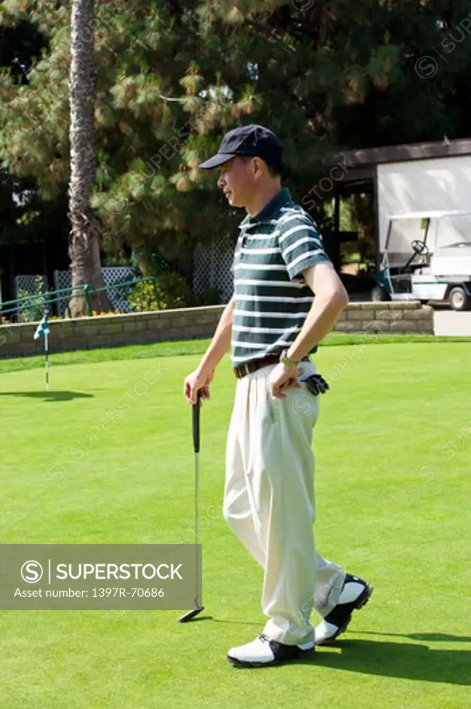 Man standing on the lawn with golf swing and looking away