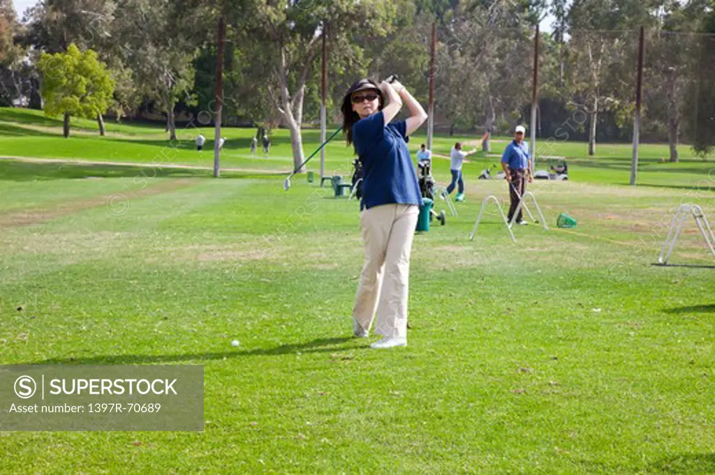Woman swinging with golf swing and looking at the camera