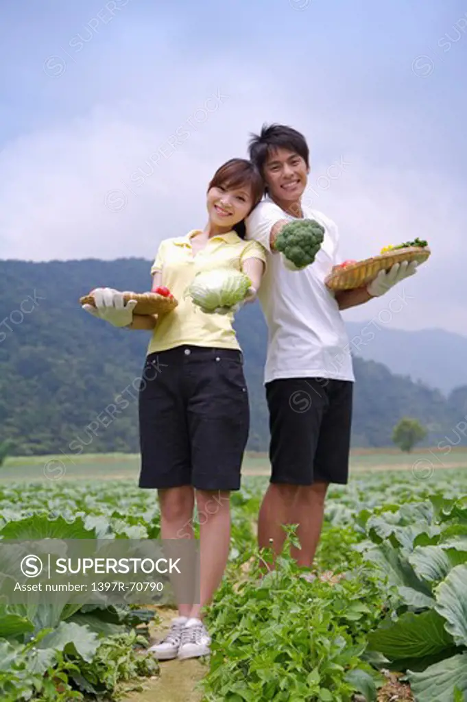 Young couple holding vegetables and smiling at the camera