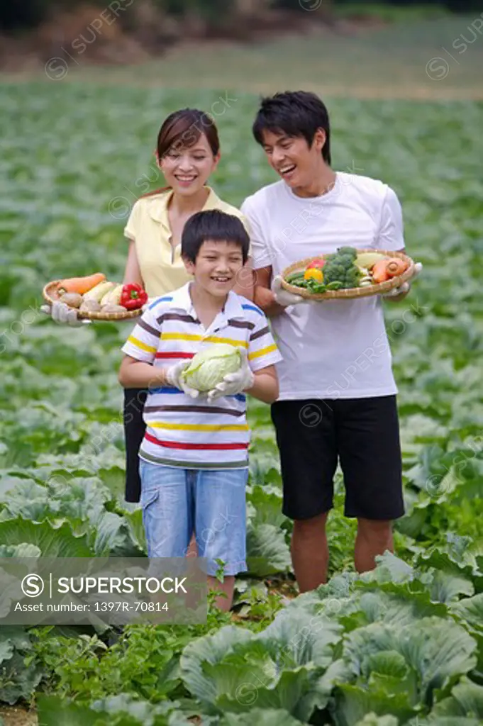 Young couple with one child holding vegetables and smiling happily
