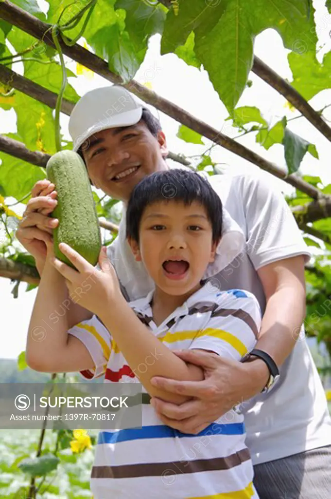Man and boy holding vegetable and looking at the camera
