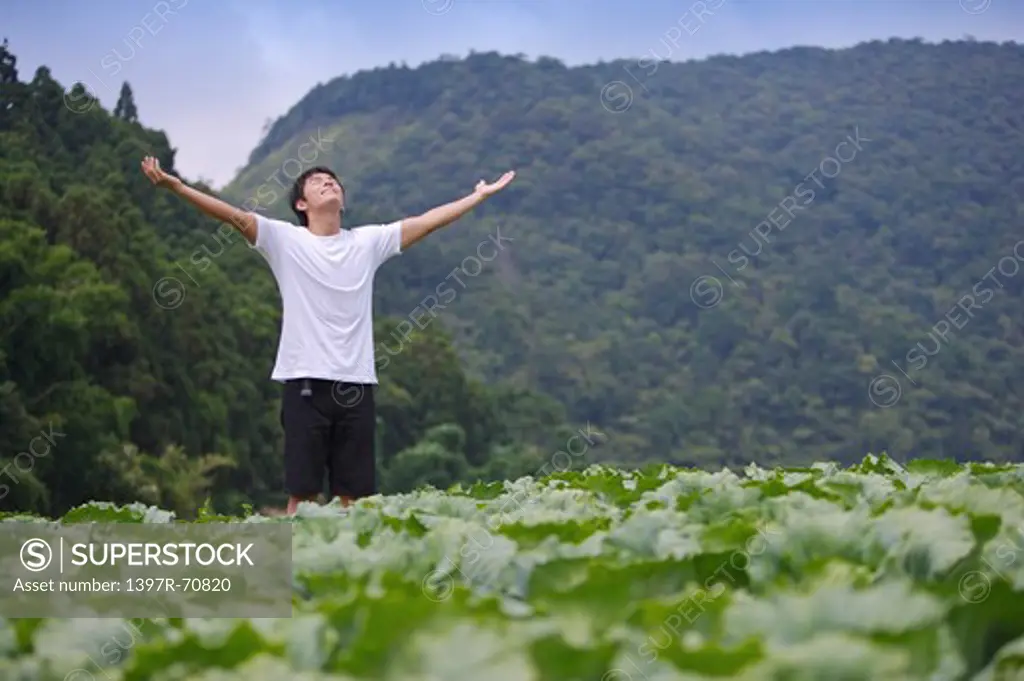 Young man standing in the vegetable garden and deep breathing