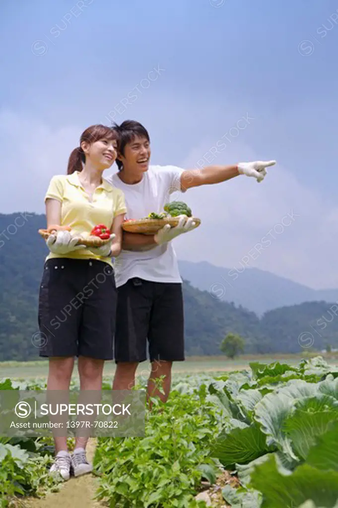 Young couple holding vegetables and smiling happily