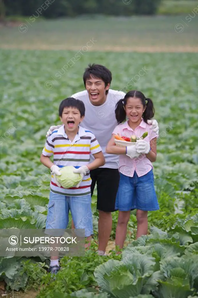 Young man with two children holding vegetables and smiling happily