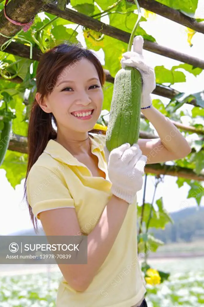 Young woman harvesting and smiling at the camera