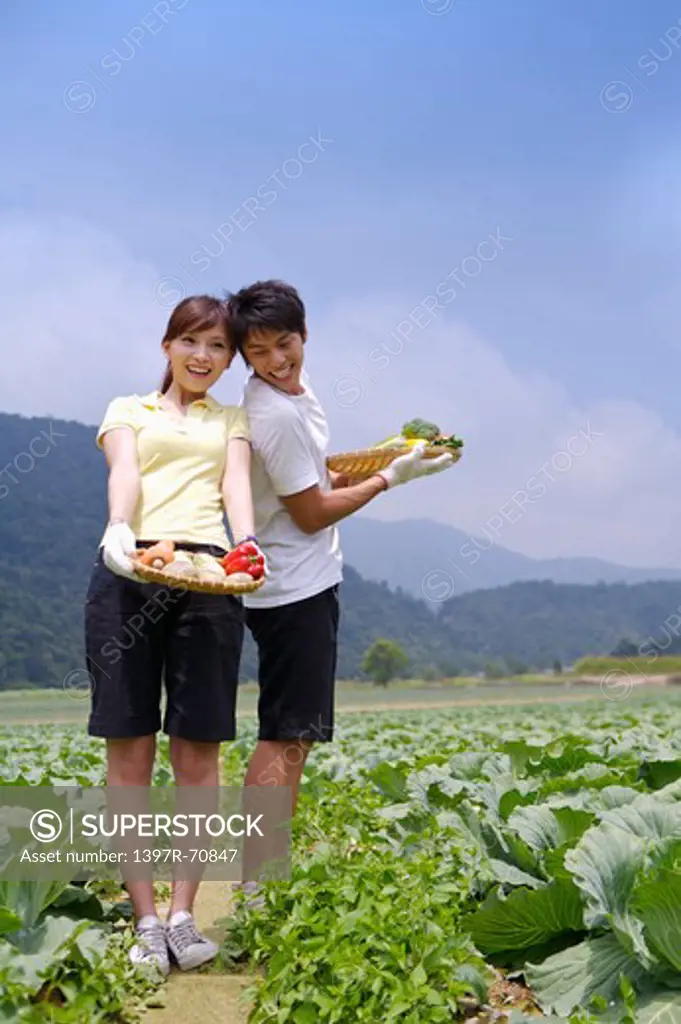 Young couple holding vegetables and smiling together