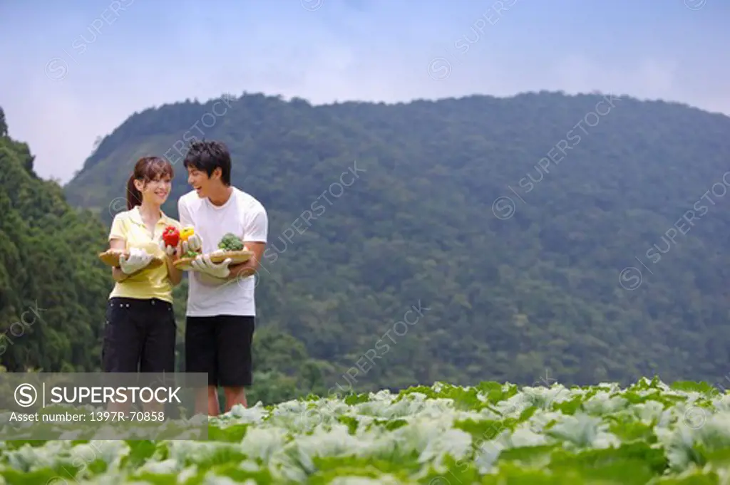 Young couple holding vegetables and smiling at each other
