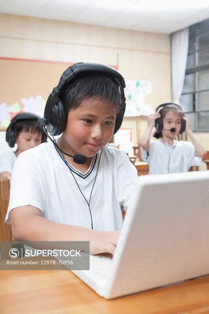 Three children using laptop with headphone together