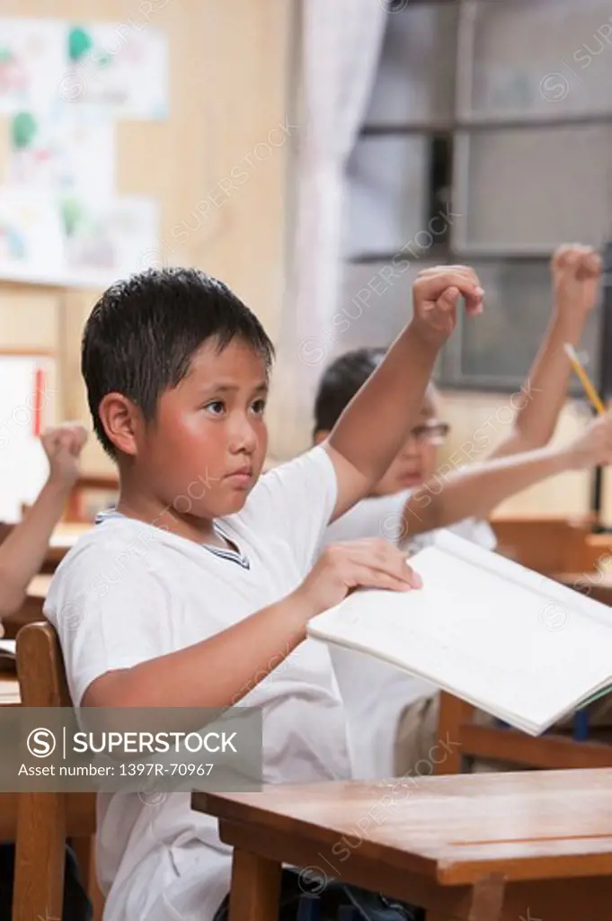 Children studying in the classroom with arms raised