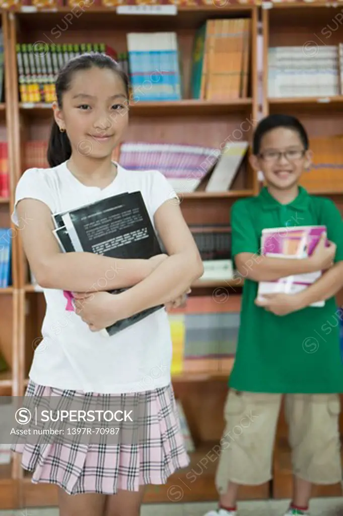 Children holding books and standing in the library
