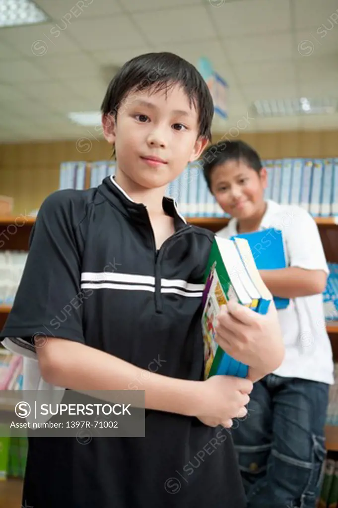 Children holding books in the library and looking at the camera together