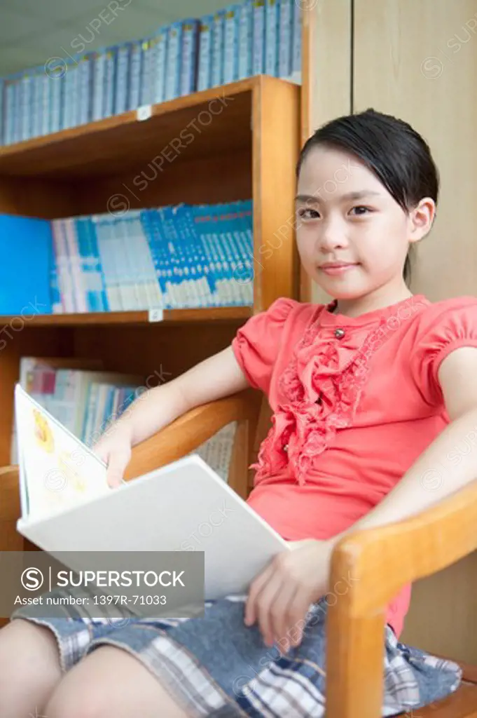Girl sitting and reading book in the library