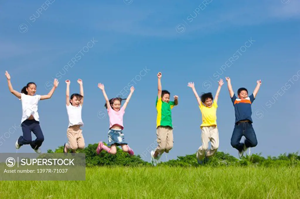 Group of children jumping in mid air on lawn