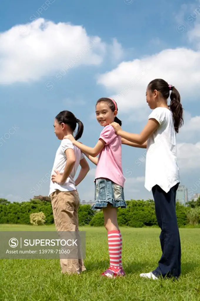 Three girls standing in a row, hands on shoulders