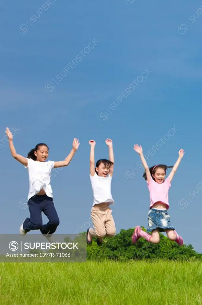 Three girls jumping in mid air on lawn