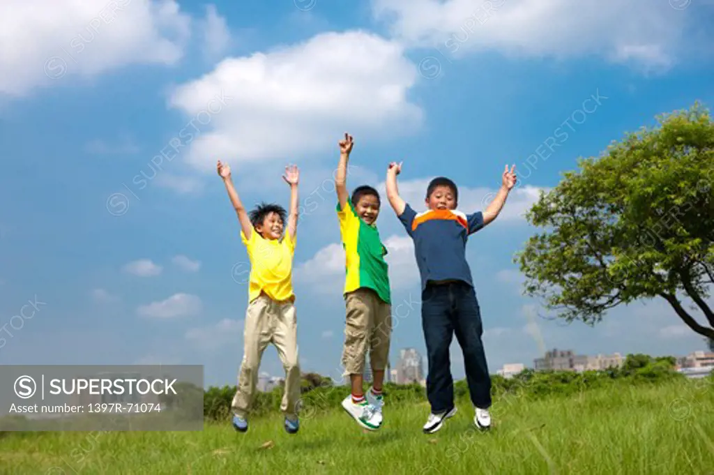 Three boys jumping in mid air on lawn