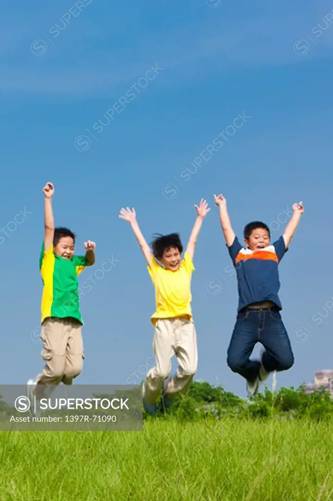 Three boys jumping in mid air on grass