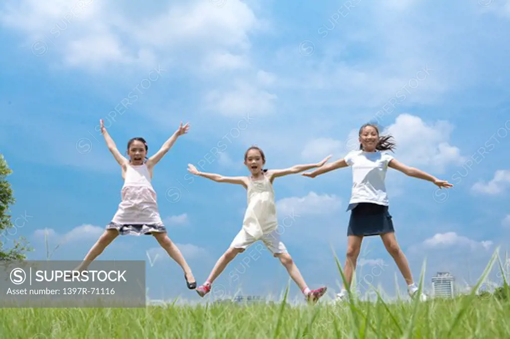 Three girls jumping in mid air on grass