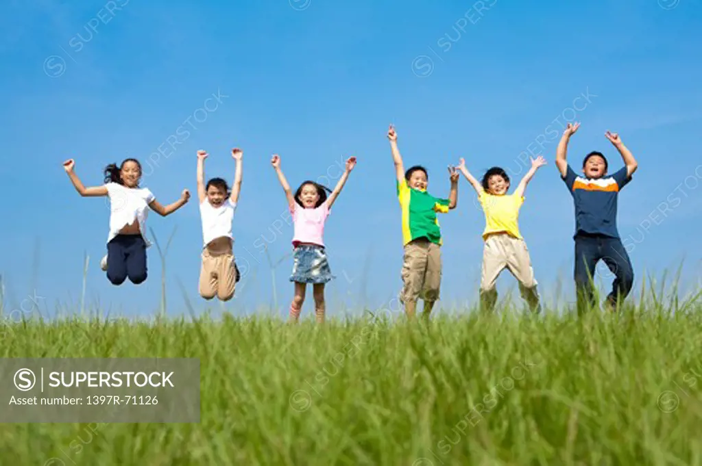 Group of children jumping in mid air on grass