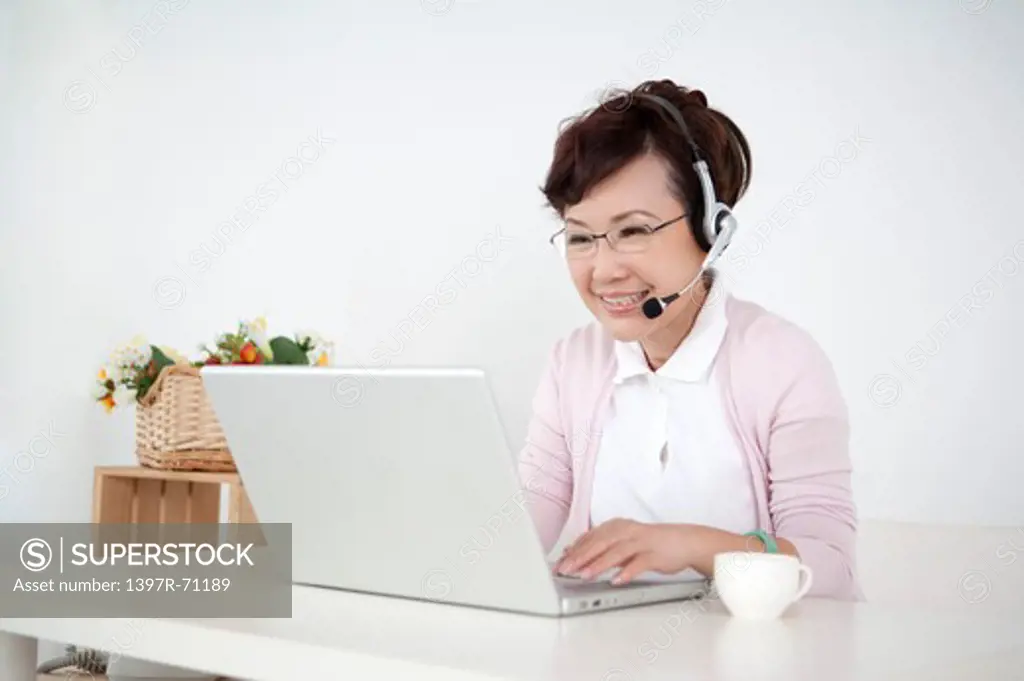 Senior woman using laptop with headphone