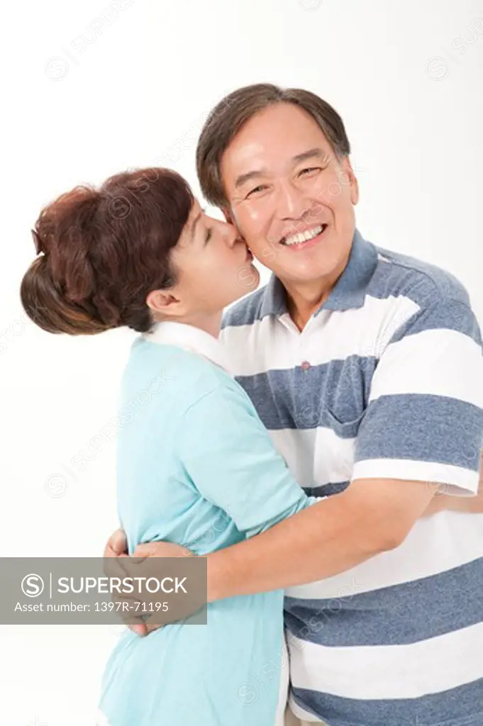 Senior couple embracing, wife kissing husband