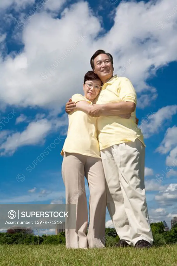 Senior couple standing on lawn and embracing together