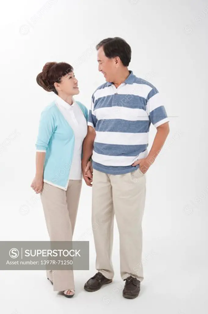 Senior couple standing together hand in hand smiling at each other