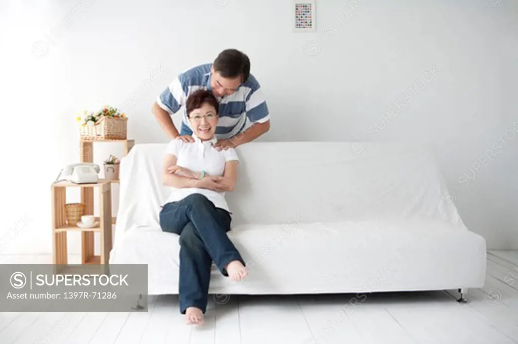 Senior man massaging wife's shoulders in living room