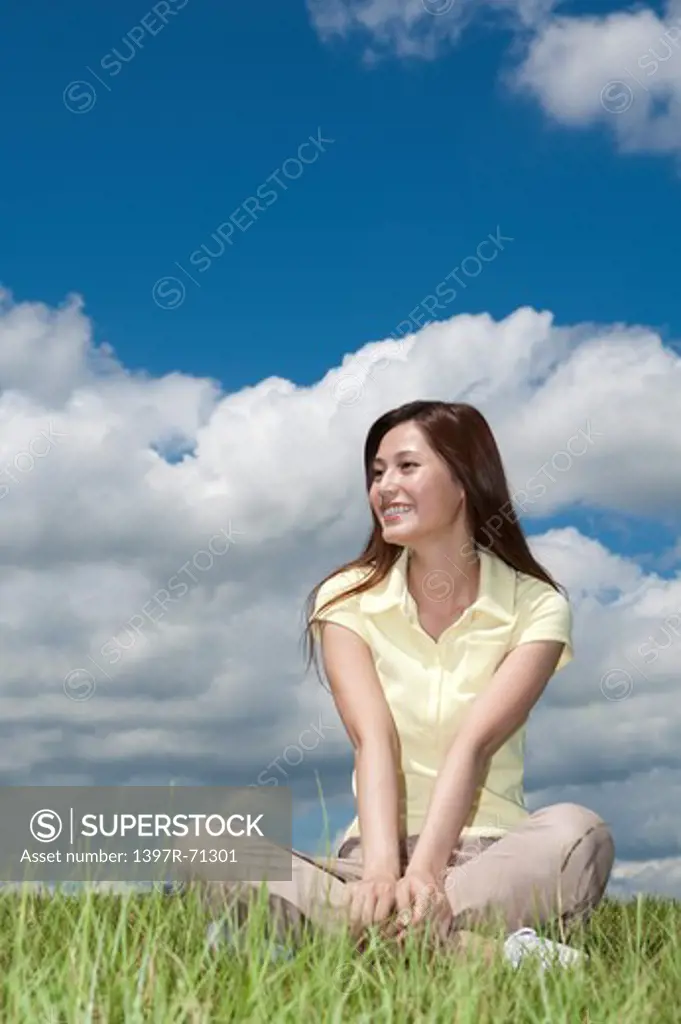 Young woman sitting on grass and looking away