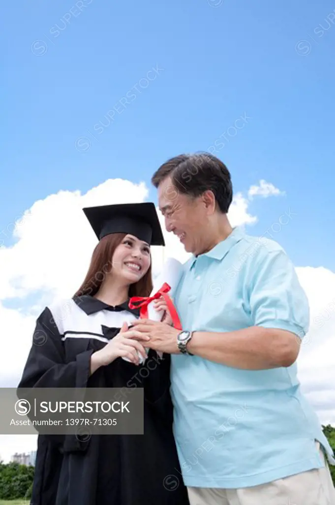 Father and daughter holding diploma together and smiling happily