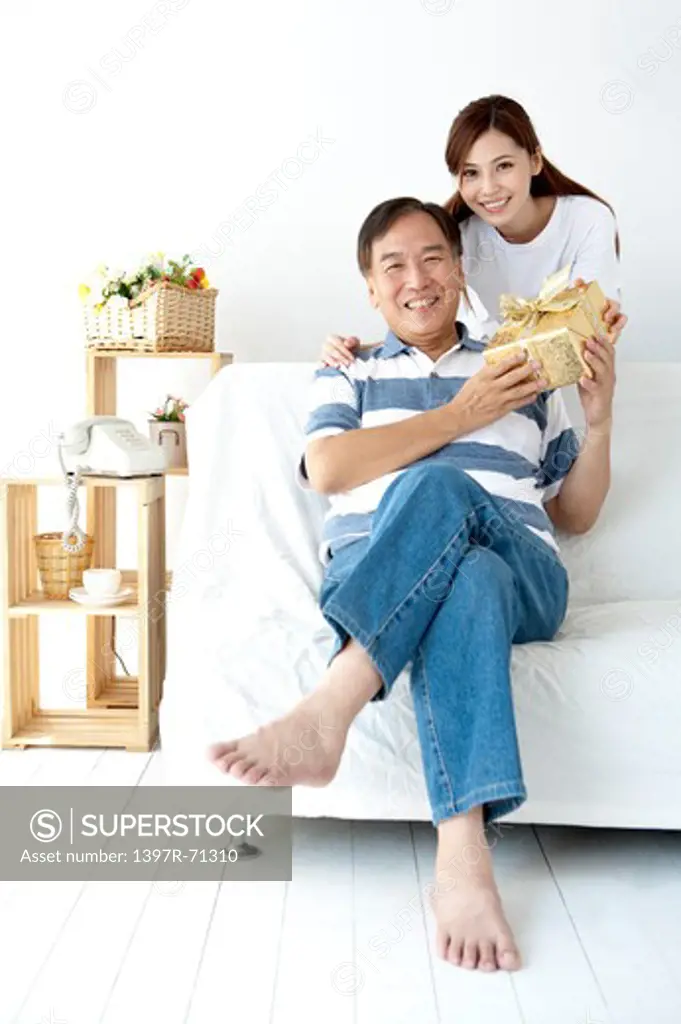 Father receiving a gift and smiling happily with daughter