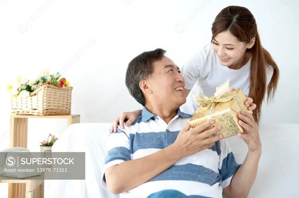 Father holding a gift and smiling with daughter