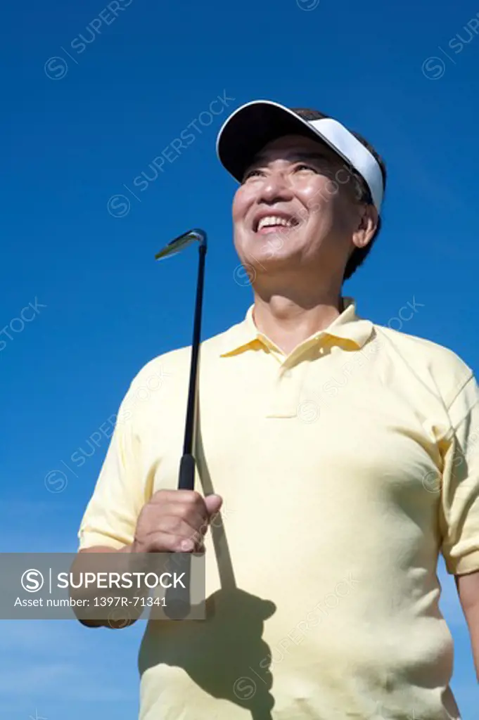 Senior man holding golf swing and looking up with smile