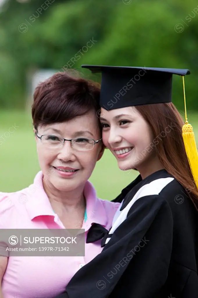 Mother and daughter looking away and smiling happily on graduation