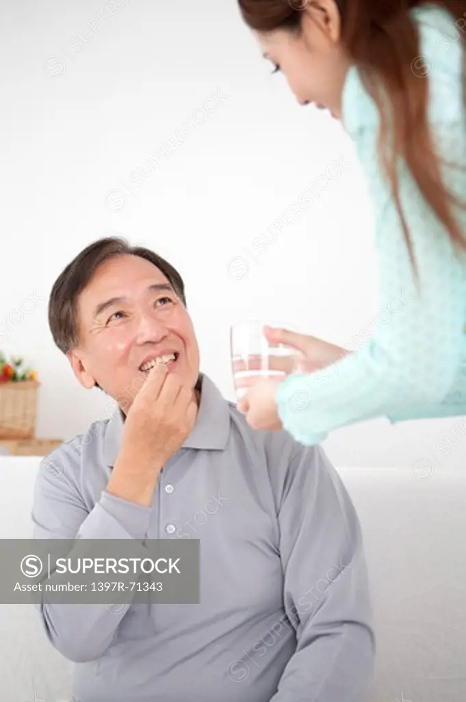Daughter giving a glass of water to father