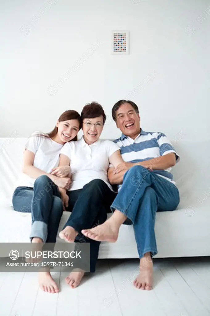 Parents with daughter sitting on sofa and smiling together