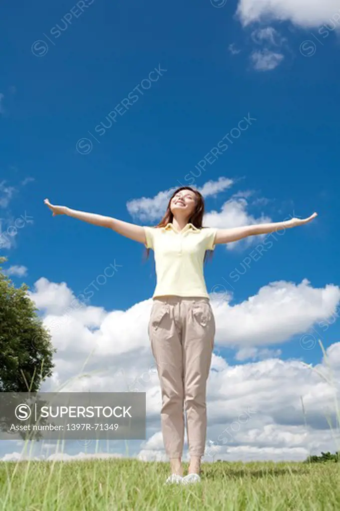 Young woman standing with arms outstretched and closing eyes